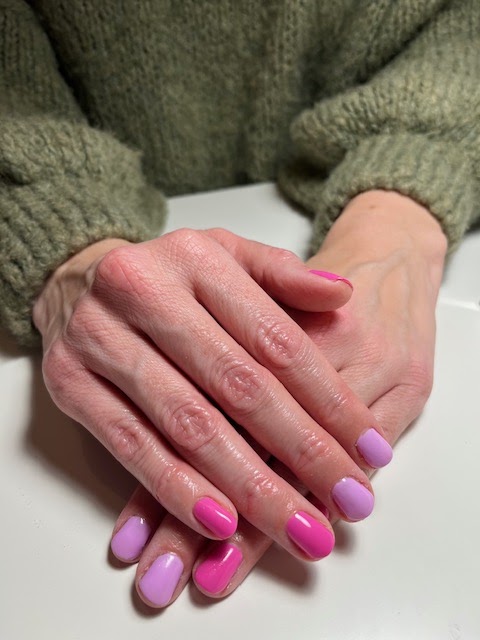 Handen met roze en lila gelnagels op een witte tafel