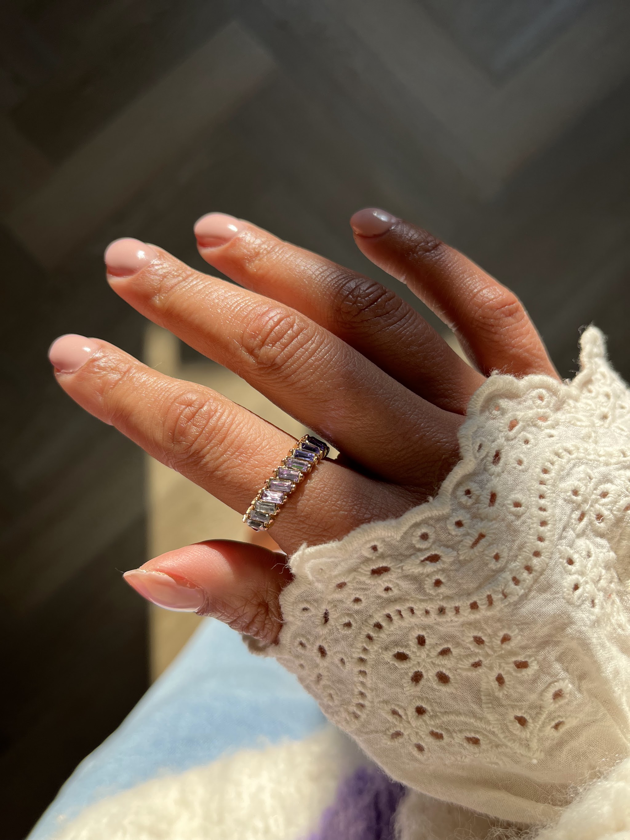 Hand met naturel roze gelnagels en een kanten mouw