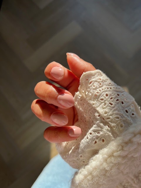Hand met roze en perzikkleurige gelnagels