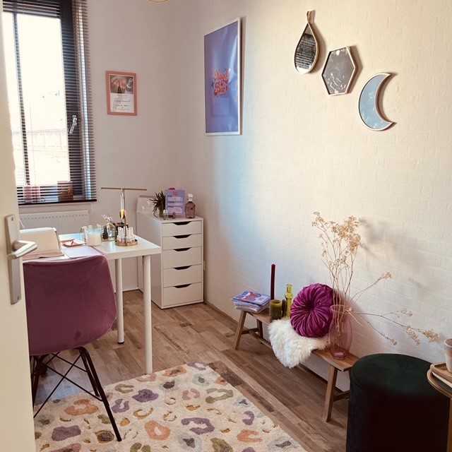 De studio van De Nagelbar: een wit bureau met lamp en flesjes, een roze stoel, spiegels aan de muur en een luipaardkleed